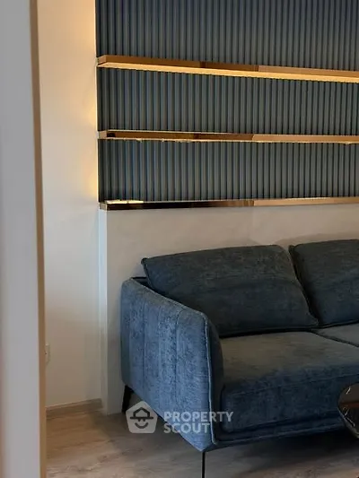 Stylish modern living room with elegant blue sofa and decorative wall shelving.