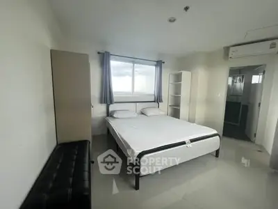Spacious bedroom with modern furnishings and large window offering natural light.