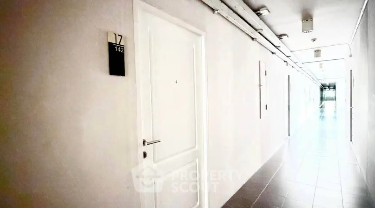 Modern apartment corridor with sleek white doors and tiled flooring, offering a clean and minimalist design.