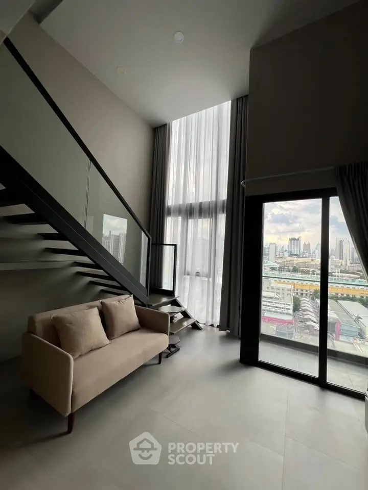 Modern loft apartment with high ceilings and city view, featuring a cozy sofa and staircase.