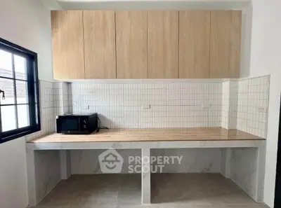 Modern kitchen with wooden cabinets and tiled backsplash, featuring a microwave on a spacious countertop.