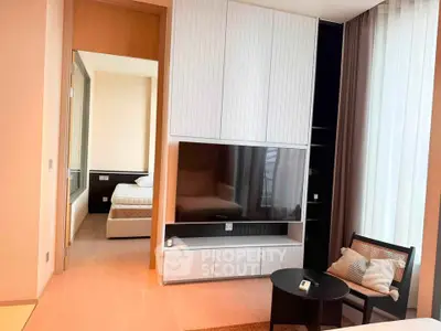 Modern living room with sleek TV unit and view into cozy bedroom
