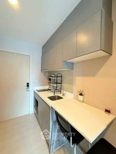 Modern compact kitchen with sleek cabinetry and integrated appliances in a stylish apartment.