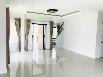 Spacious modern living room with large windows and staircase, perfect for family gatherings.