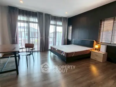 Spacious bedroom with large windows and modern furnishings in a stylish apartment.