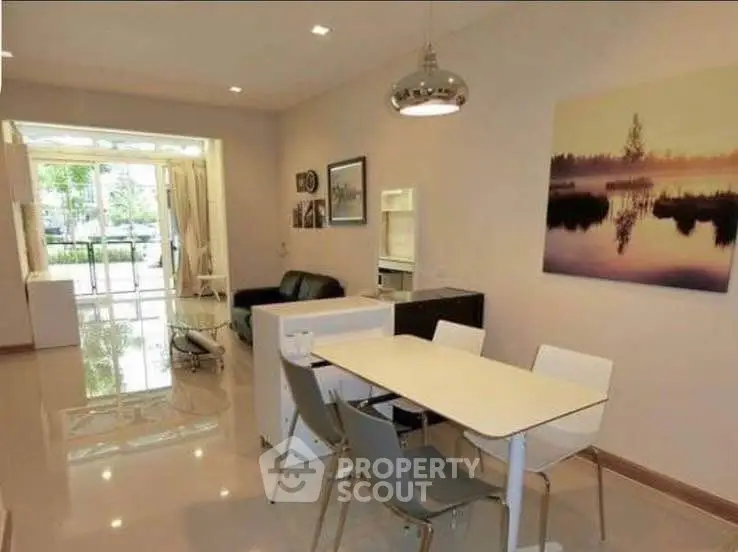 Modern dining area with sleek furniture and natural light in open-plan living space.
