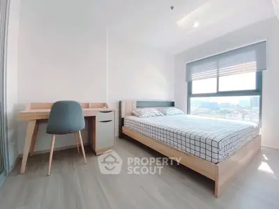 Modern bedroom with large window and stylish furniture in a bright apartment.