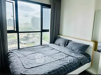 Modern bedroom with large window offering stunning city view in high-rise apartment.