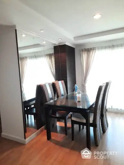 Elegant dining area with modern table and chairs, featuring large mirror and natural light.