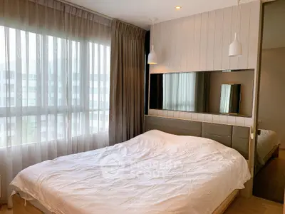 Modern bedroom with large window and stylish lighting in a contemporary apartment.