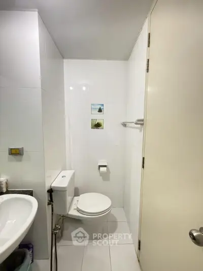 Compact bathroom with modern fixtures and white tiles, featuring a toilet and sink.