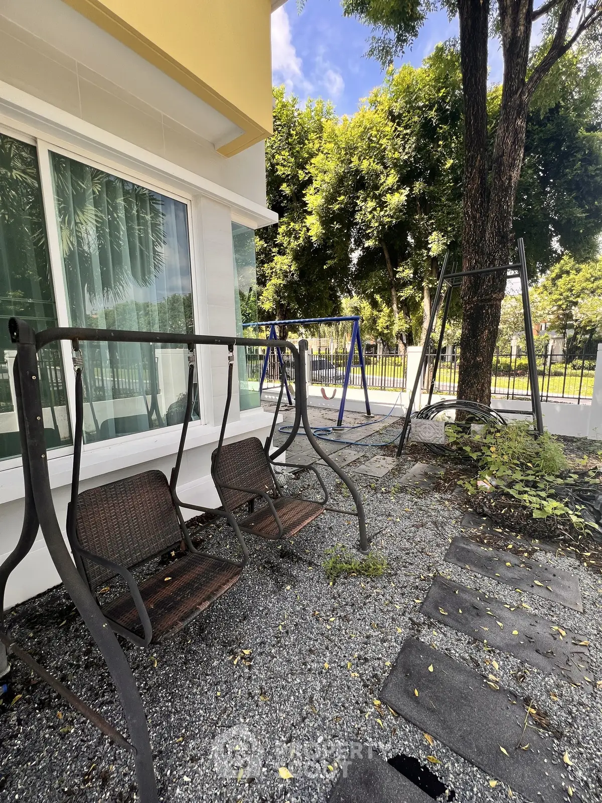 Charming outdoor garden area with swings and lush greenery, perfect for relaxation and leisure.