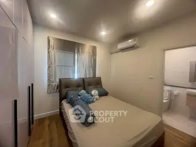 Cozy bedroom with modern decor and ensuite bathroom, featuring soft lighting and air conditioning.