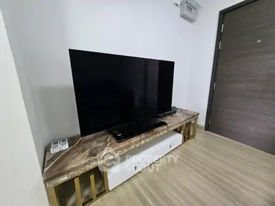 Modern living room with sleek TV on stylish marble console and elegant wooden flooring.