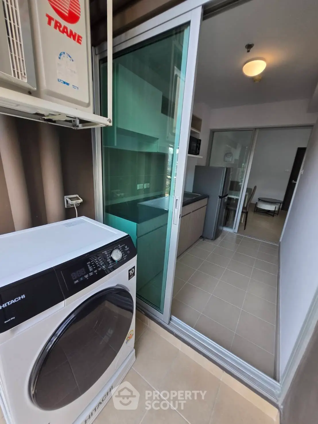 Modern condo with balcony featuring washing machine and sliding glass door to kitchen.