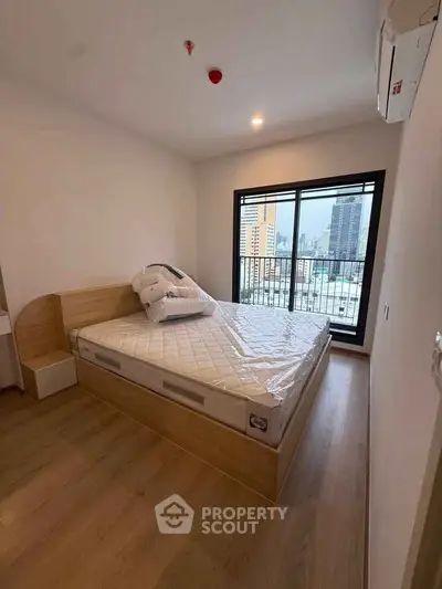 Modern bedroom with city view and wooden flooring in a high-rise apartment.