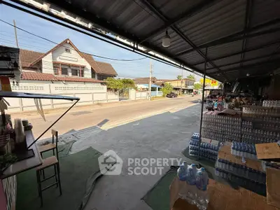 Street view from a covered outdoor area with bottled water and residential houses in the background.