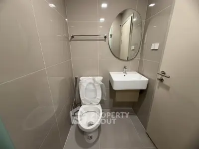 Modern bathroom with sleek design featuring a round mirror and compact sink.