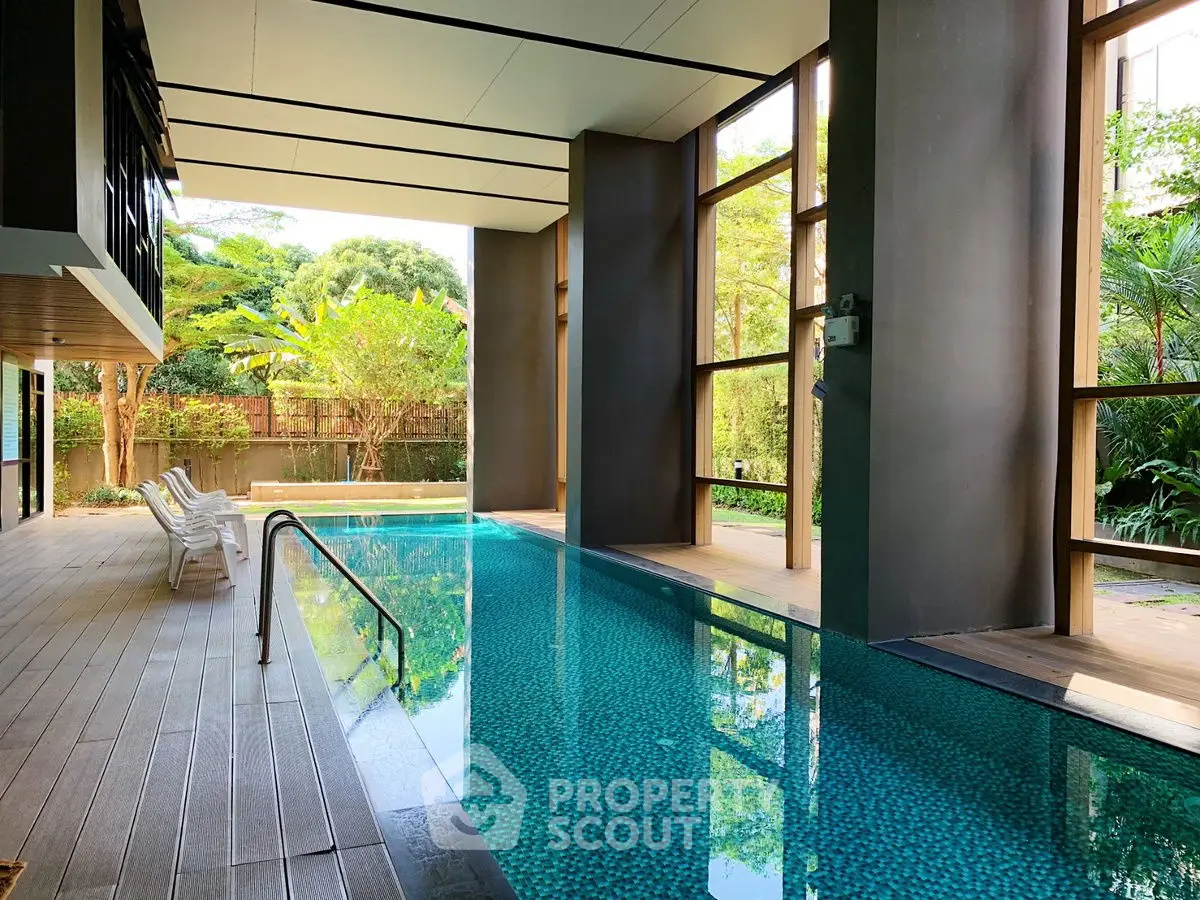 Luxurious indoor pool area with modern design and lush greenery views.
