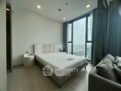 Modern bedroom with large window offering stunning city views, featuring a comfortable bed and stylish decor.