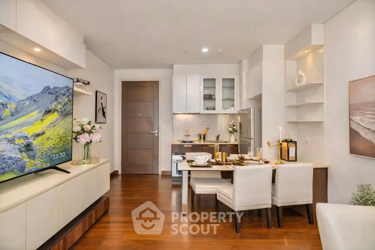 Modern open-layout living room with stylish kitchen and dining area, featuring elegant decor and wooden flooring.