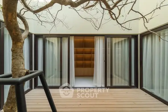 Modern courtyard with wooden deck and glass doors leading to interior space.