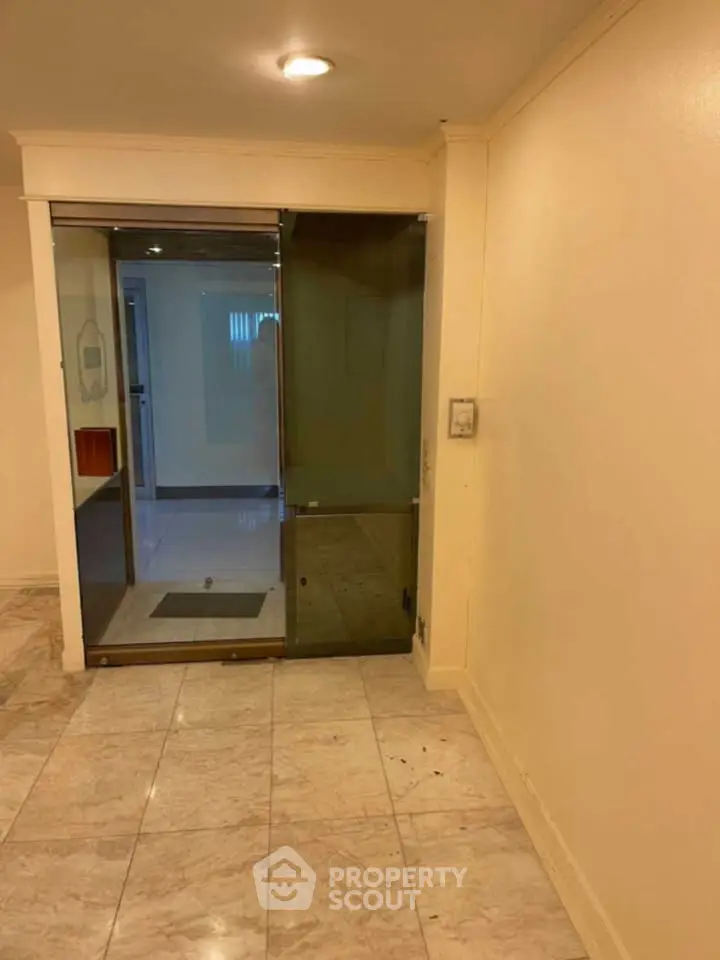 Elegant building entrance with sleek glass door and marble flooring
