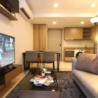 Modern living room with open kitchen, cozy seating, and stylish decor in a contemporary apartment.