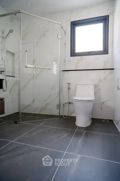 Modern bathroom with sleek design, featuring a glass shower enclosure and elegant tile flooring.
