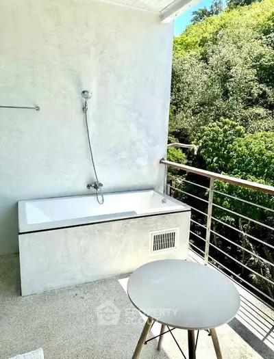 Charming outdoor balcony with bathtub and lush green view, perfect for relaxation and tranquility.