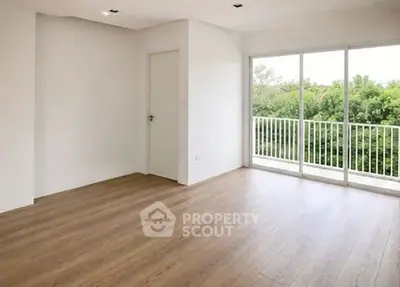 Spacious empty room with large windows and balcony overlooking greenery, perfect for customization.