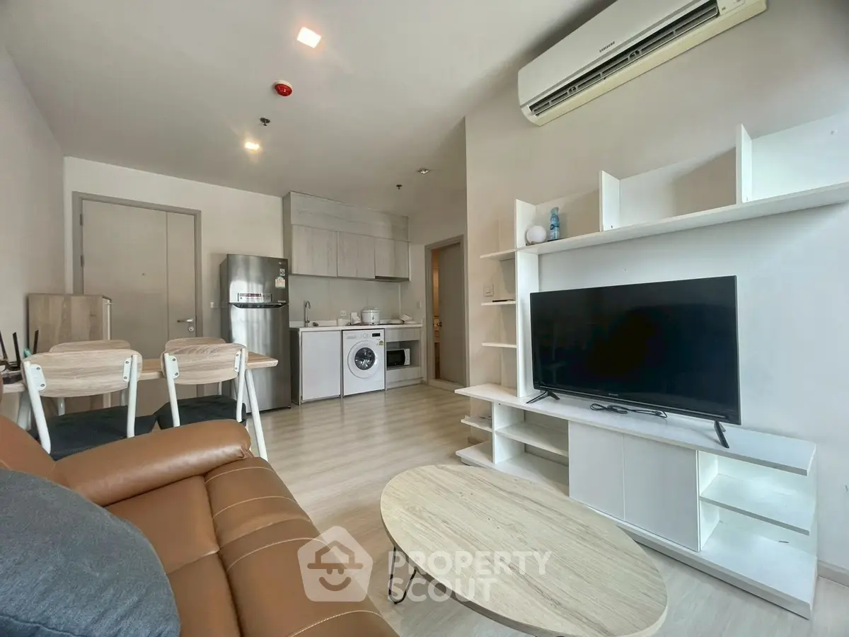 Modern living room with open kitchen, featuring sleek furniture and appliances, ideal for urban living.