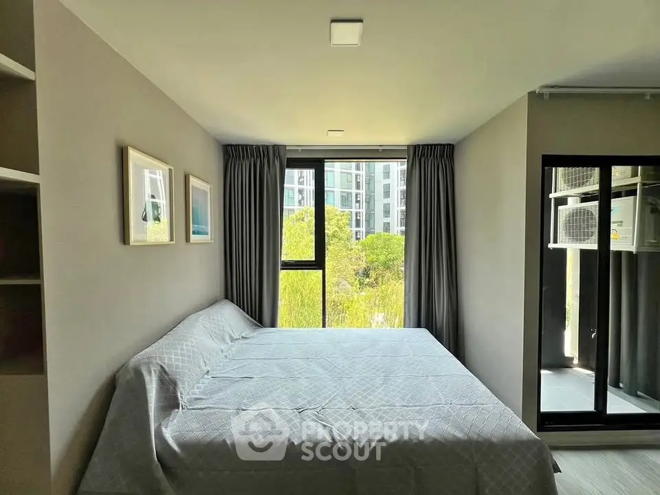 Modern bedroom with large window and minimalist decor in a high-rise apartment.