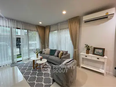 Elegant living room with modern decor, featuring a cozy sofa, stylish rug, and large windows with sheer curtains.