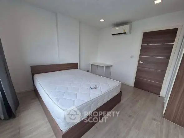 Modern minimalist bedroom with wooden flooring and air conditioning