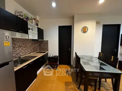 Modern kitchen with sleek black cabinets and dining area in contemporary apartment.