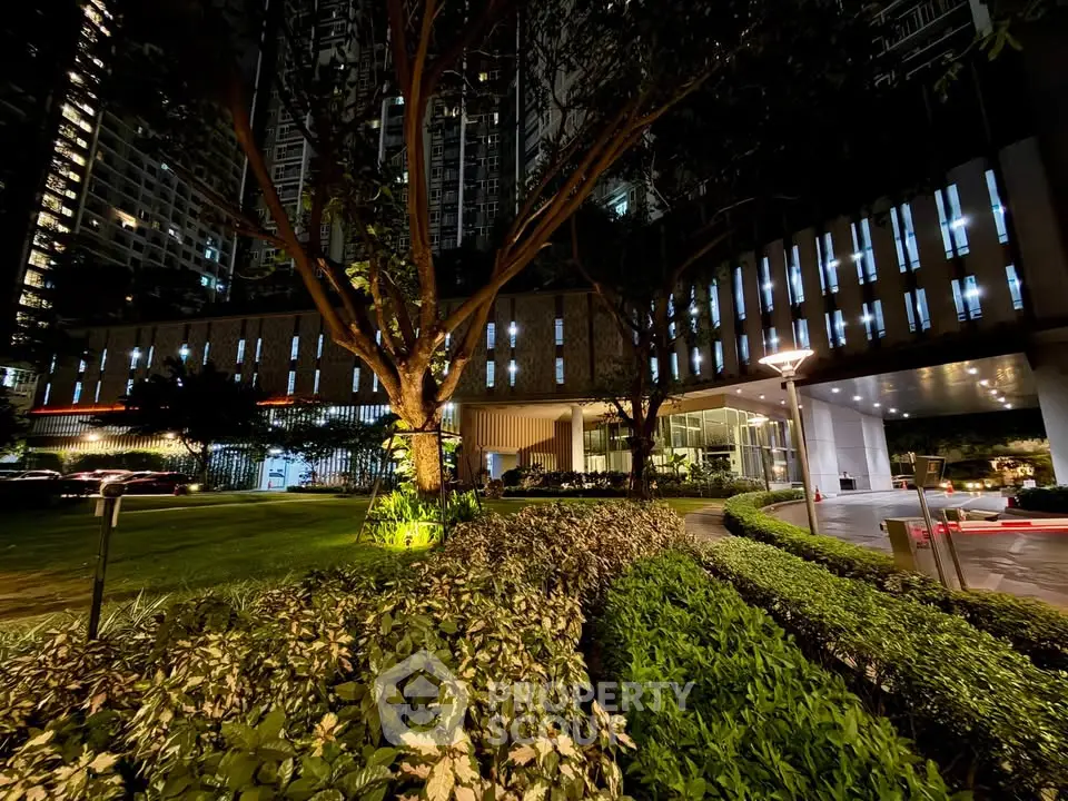 Stunning night view of modern building entrance with lush landscaped garden