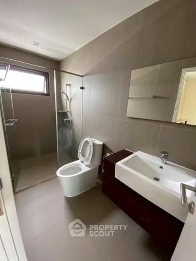 Modern bathroom with sleek fixtures and glass shower enclosure.