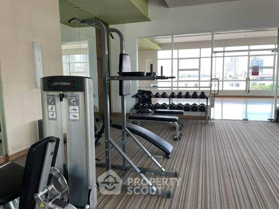 Modern gym with fitness equipment and city view in luxury apartment building.