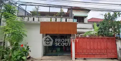 Charming two-story house with gated entrance and lush greenery in a peaceful neighborhood.