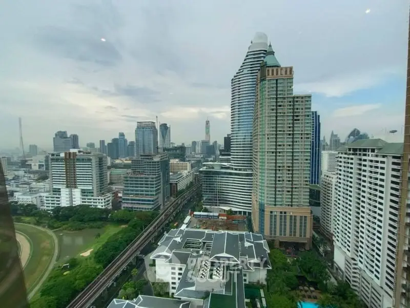 Stunning cityscape view from a high-rise building showcasing modern architecture and lush greenery.