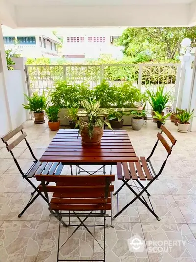 Charming garden patio with wooden furniture and lush greenery, perfect for outdoor relaxation.