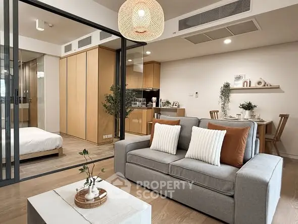 Modern open-plan living room with cozy decor and adjacent bedroom view.