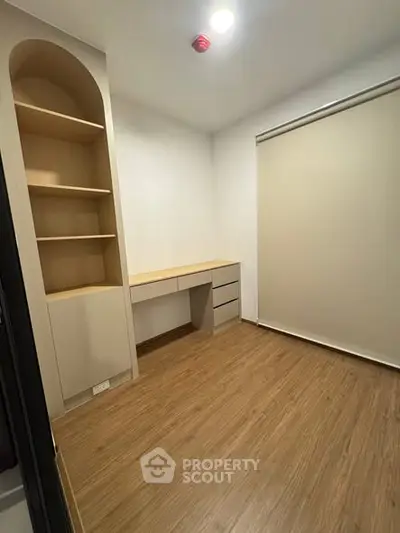 Modern study room with built-in shelves and desk, featuring wood flooring and neutral tones.