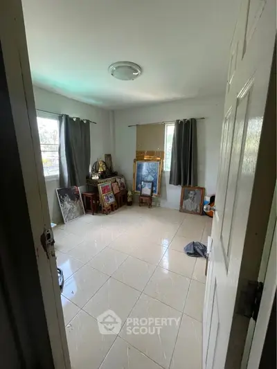 Spacious room with tiled flooring and large windows, ideal for art display or creative space.