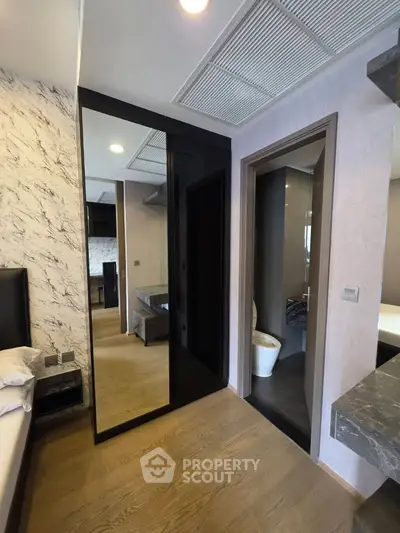 Modern bedroom with ensuite bathroom and sleek mirrored wardrobe in stylish apartment.