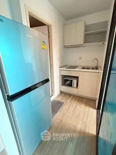 Modern compact kitchen with sleek appliances and wooden flooring