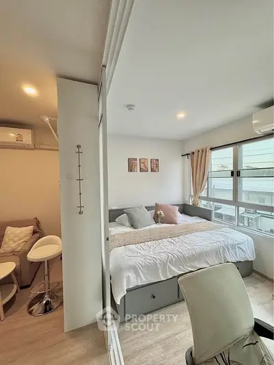 Cozy bedroom with large windows and modern decor, featuring a comfortable bed and stylish seating area.