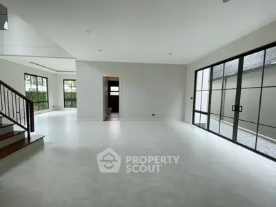 Spacious modern living room with large windows and elegant staircase