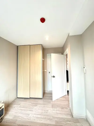 Bright minimalist bedroom with wooden flooring and built-in wardrobe